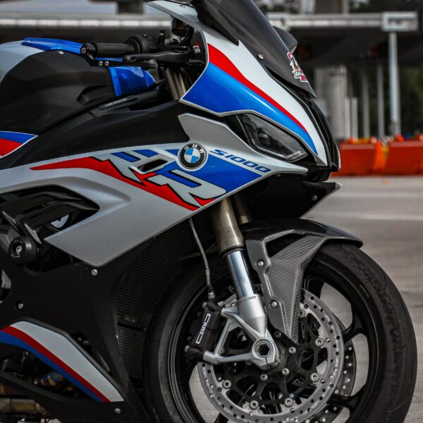 The front wheel of a red, blue and silver BMW S 1000 RR Photo by Juan Sandoval Pacheco from Pexels