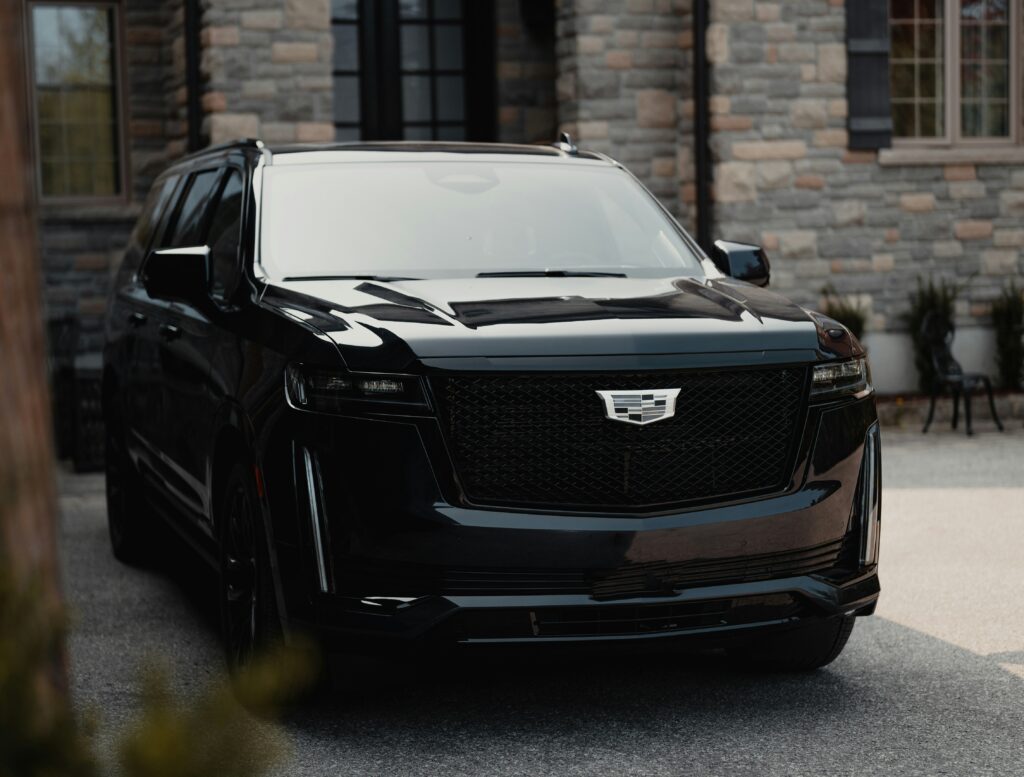 A black Cadillac Escalade parked in front of a brick house.
Photo by Franco Debartolo from Unsplash