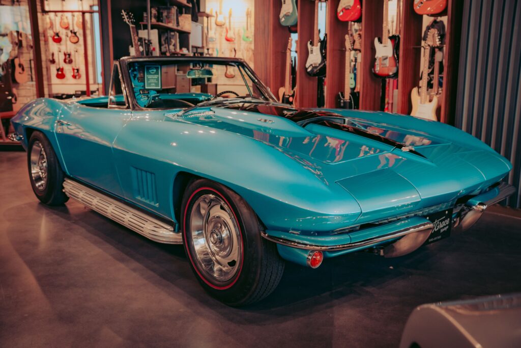 A blue Chevrolet Sting Ray in an indoor showroom surrounded by guitars.
Photo by Osmany Mederos from Pexels