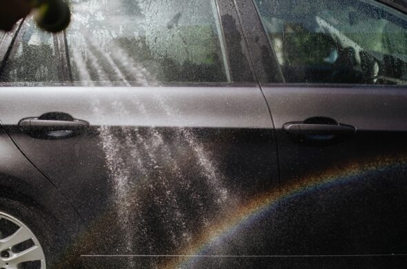 Close-up of a car being washed with a visible rainbow in sunlight. Photo by KaboomPics fromP Pexel