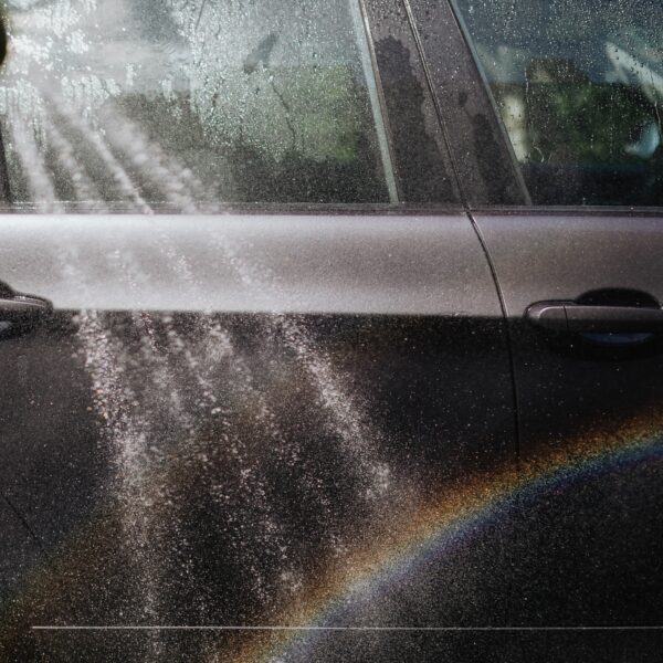 Close-up of a car being washed with a visible rainbow in sunlight. Photo by KaboomPics fromP Pexel