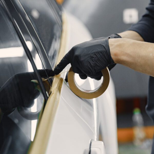 A gloved hand tapes a car in preparation for a paint job. Photo by prostooleh from Magnific
