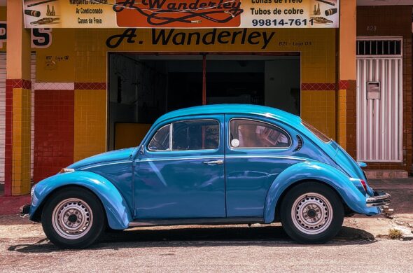A bright blue car sits on the street in front of a store front Photo by Victor Cayke from Pexels