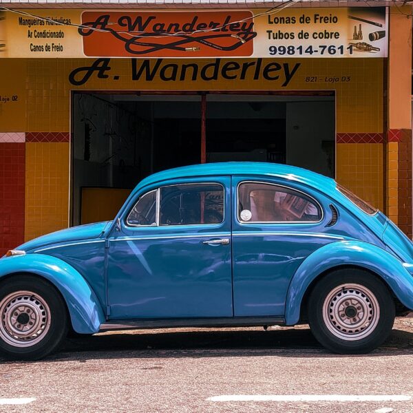 A bright blue car sits on the street in front of a store front Photo by Victor Cayke from Pexels