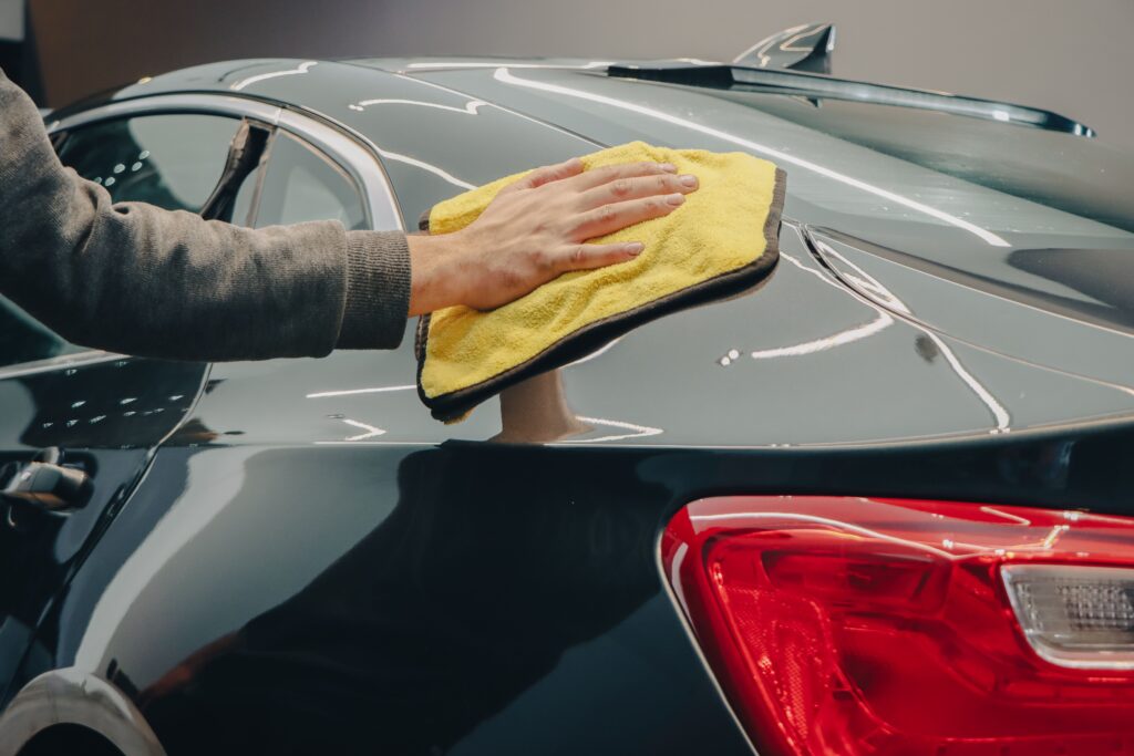 A hand polishes the back of dark blue car with a microfiber towel.
Photo by Dexstar Studio from Pexels