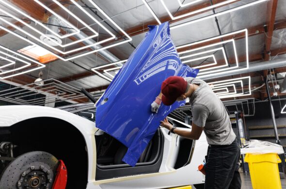 A worker wraps the door of a white sports car in a purple wrap. Photo by Auto Records from Pexels