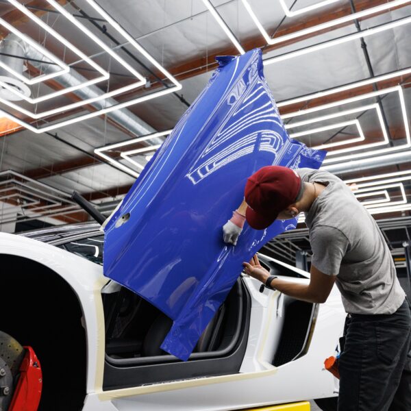 A worker wraps the door of a white sports car in a purple wrap. Photo by Auto Records from Pexels