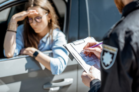 A women in the black car getting a ticket from a cop