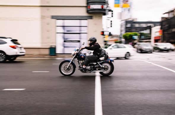 man rides a motorcycle down a street