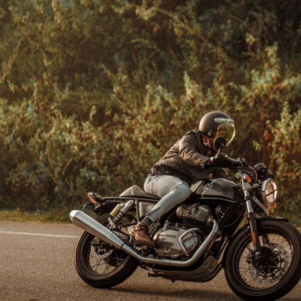 A person drives a black motorcycle on a road lined by trees Photo by Abhishek sanga from