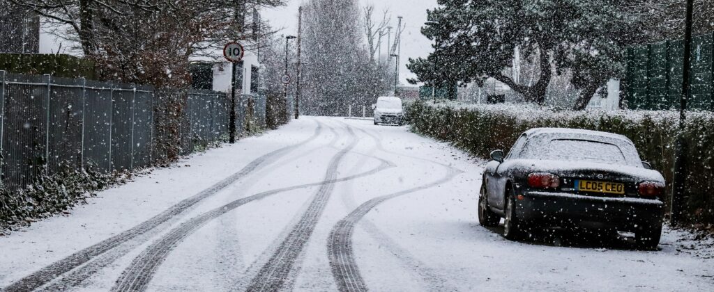 A car is parked on a tree lined street in the snow.
Photo by Samuel Field from Unsplash.