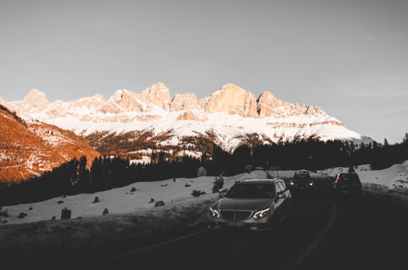 Cars drive through a snowy mountain road