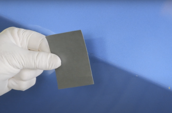 A piece of sand paper beside a blue car