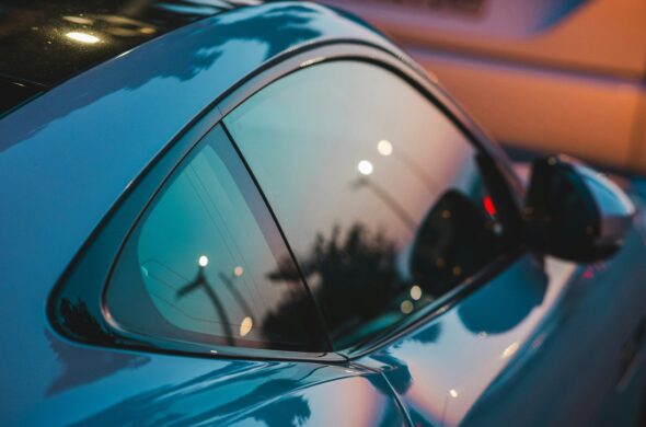 A city is reflected in the shiny coat of a blue car. Photo by Daniel Splisser from Unsplash