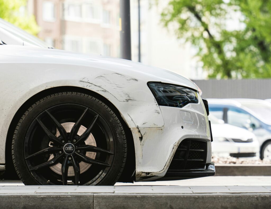 The front of a badly scratched white car Photo by Volodymyr Dobrovolskyy from Unsplash