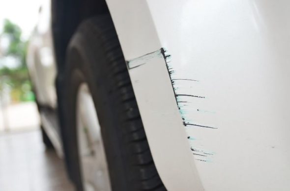 A photo of a white car focusing on the scratched part