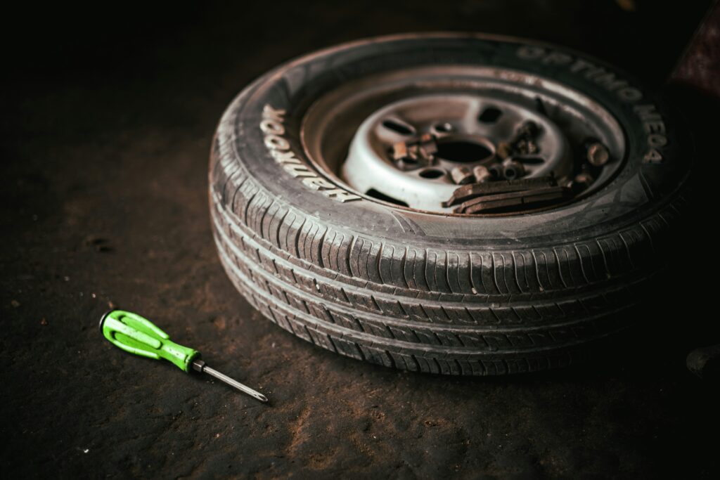 A wheel sits on the ground next to a green screwdriver. Photo by Tahamie Farooqui from Unsplash