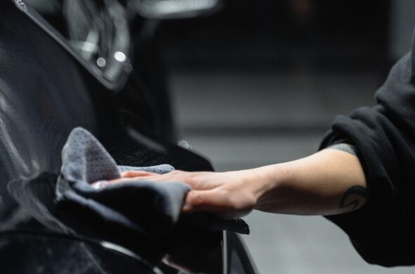 A hand wipes down a black car with a cloth. Photo by Tima Miroshnichenko from Pexels