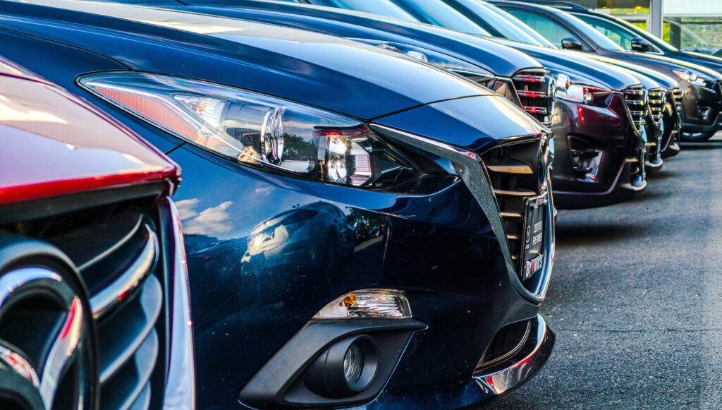 A row of shiny used cars parked side by side. Photo by Obi from Unsplash