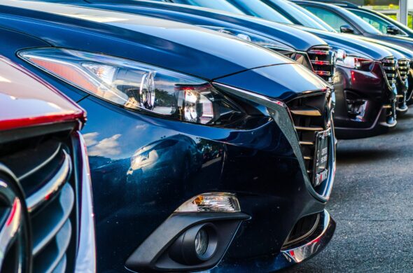 A row of shiny used cars parked side by side. Photo by Obi from Unsplash