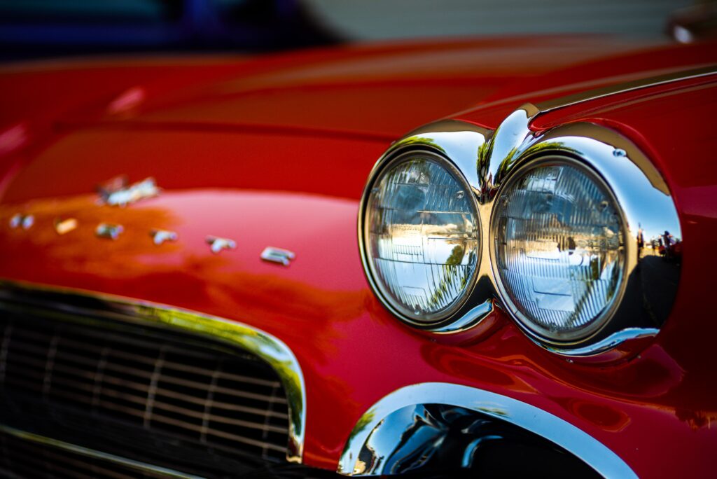 Detailed close-up of classic red Corvette car headlights showcasing vintage design and chrome details. Photo by Bryce Carithers from Pexels