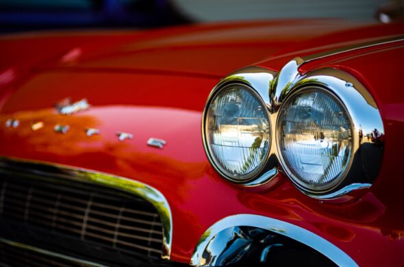 Detailed close-up of classic red Corvette car headlights showcasing vintage design and chrome details. Photo by Bryce Carithers from Pexels