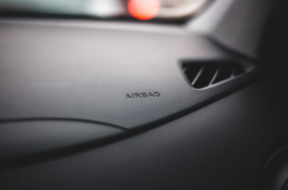 The front console of a car's interior helpfully identifies where the airbag is. Photo by Erik Mclean from Pexels