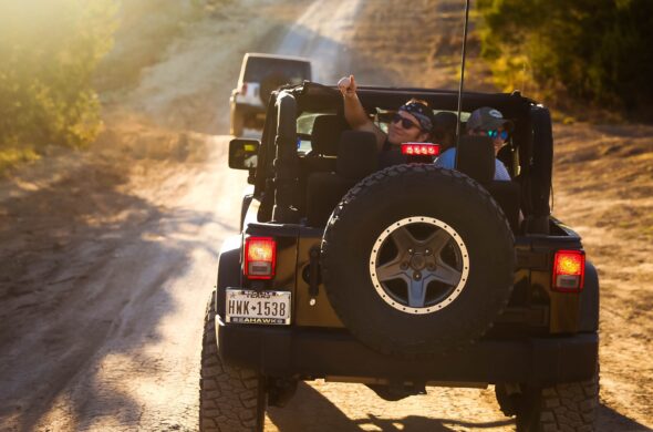 A group of friends in a Jeep greet people the car behind them. Photo by Oliver Schlotfeldt from Pexels