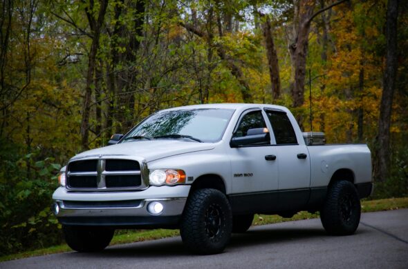 A white Ram 1500 parked on a road by the woods. Photo by Chris Marlin from Unsplash