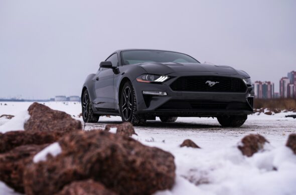 A black Mustang parked in the snow. Photo by Vitali Adutskevich from Unsplash