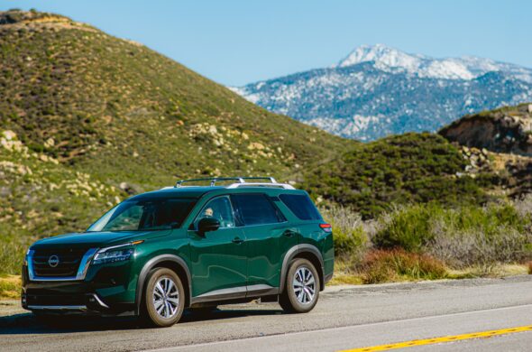 Green Nissan Pathfinder SUV on a road near lush mountains against a clear blue sky. Photo by Ritesh Singh from Pexels