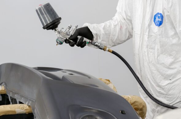 A hand spray paints a gray car panel. Photo by Mohammad Hammad from Pexels