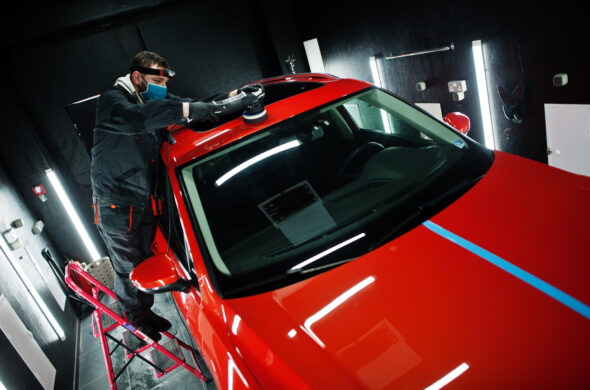 A worker in a body shop details a red car. Photo by ASphotofamily