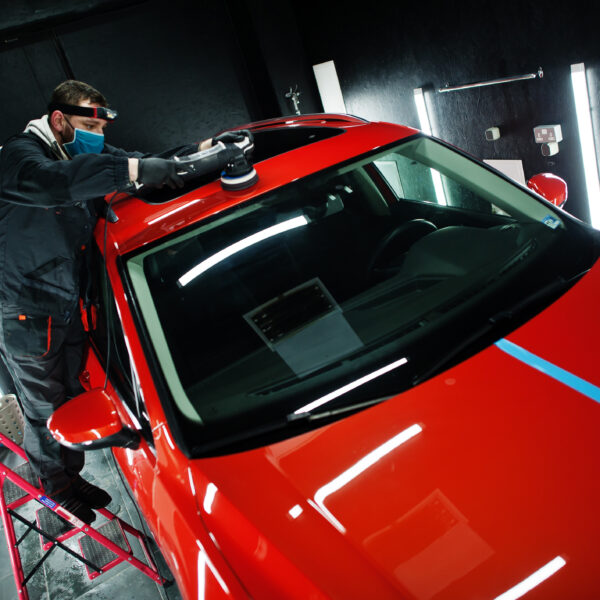 A worker in a body shop details a red car. Photo by ASphotofamily