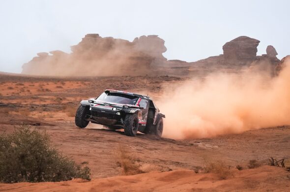 A dynamic off-road rally car kicking up dust on a desert landscape with rock formations. Photo by Fatih Dağlı