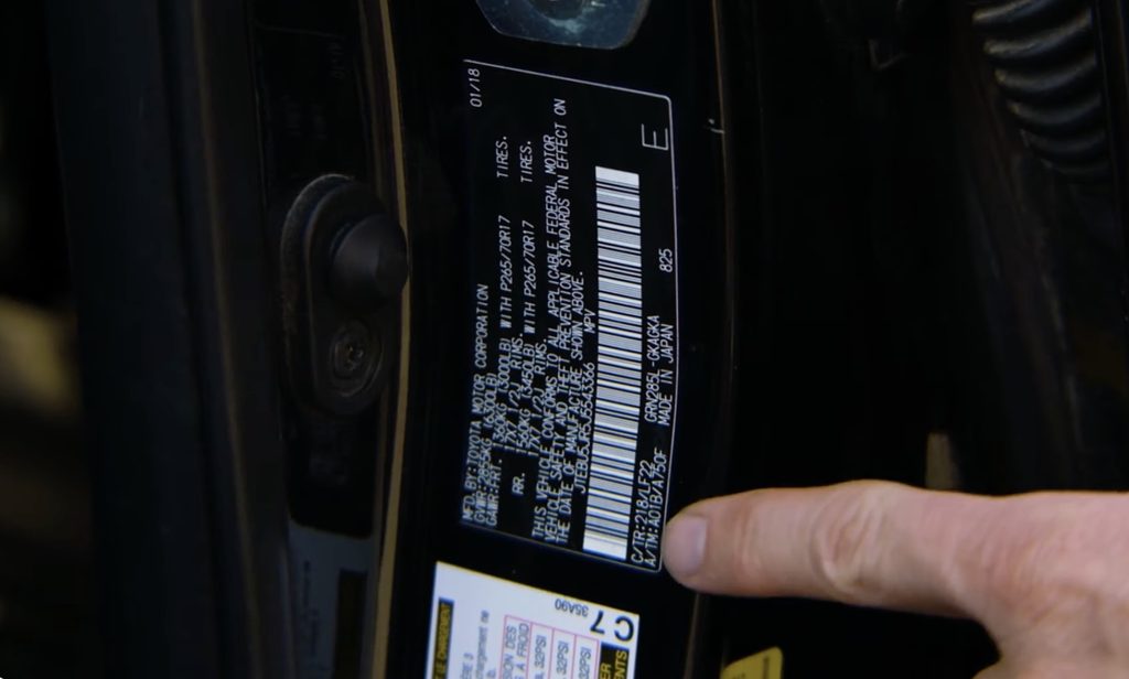 A finger points to a Toyota TRD Pro paint code on a driver door jamb sticker